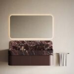 Backlit rectangular mirror above a burgundy marble vanity in a minimalist bathroom.