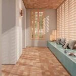 Sunlit spa-like room with a teal bench and cushions along a wall of wooden lattice panels, warm wood floors and ceiling, and sunlight streaming through a lattice window.